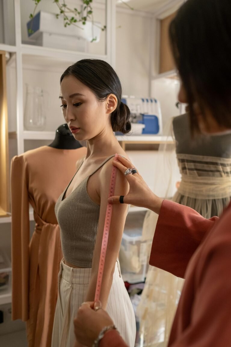 A fashion designer measures a model in a studio for a dress fitting session.